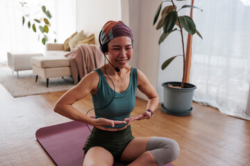 Woman with headset leads online yoga class at home.