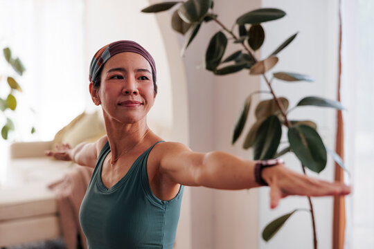 Woman in warrior pose, plants in background.