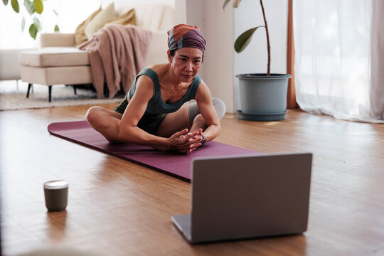 Woman doing yoga at home with online class.