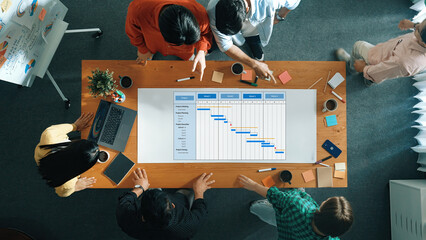 Collaborative Team Meeting for Project Management with Gantt Chart and Discussion Over Table in Modern Office Space. Amity