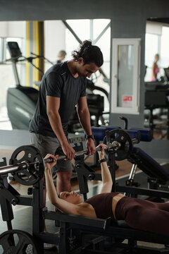 Young Trainer Spotting Woman During Bench Press