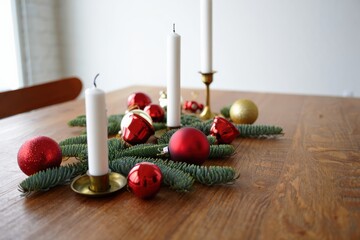 Christmas table setting with candles, ornaments, and pine branches creating festive atmosphere