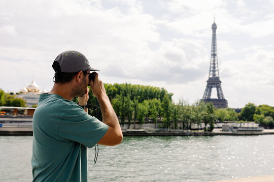 Wide shot of visitor in the foreground photographing the Eiffel Tower