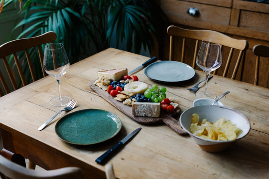 Dinner table with wine glasses, raw salmon and assorted French cheeses