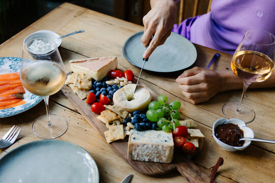 Close-up of hands arranging French cheeses on a platter