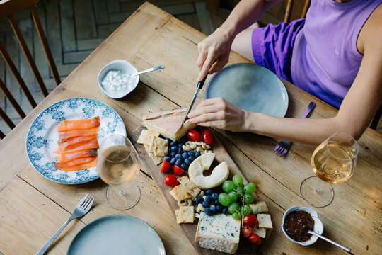 Unknown woman preparing a platter of French cheeses to enjoy with wine