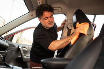 Man Cleaning Car Seats With an Orange Cloth