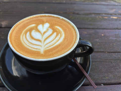 Cup of coffee latte with intricate foam art of heart shape on old, seen from above