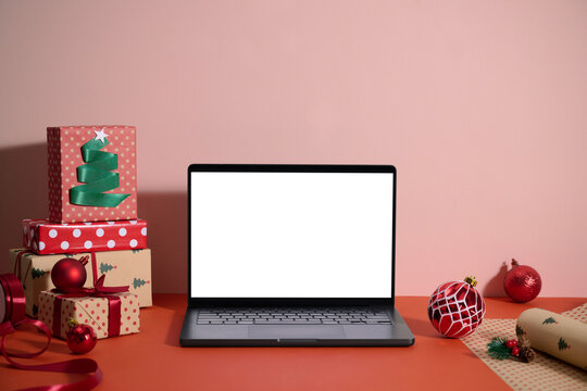 Laptop with a blank screen, surrounded by Christmas gifts