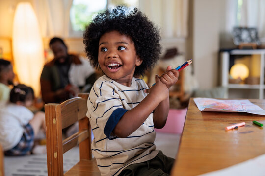 Happy child drawing with crayons at a table.