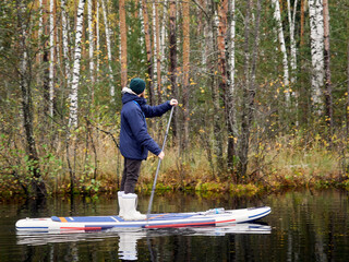 Autumn paddleboarding through swamp forest