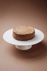 Chocolate cake with heart shaped decor on stand, minimal brown background
