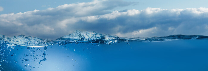Sea water surface and underwater view. Sky with clouds above