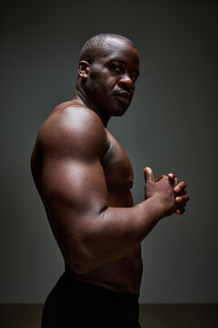 Strong man posing against a dark backdrop in a studio setting