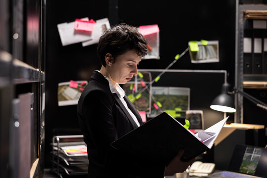 Female criminologist collecting intelligence for a secret mission, linking different evidence with classified documents on a mystery board. Tracing illegal activity and pursuing a criminal case.