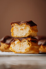 Close up of stacked chocolate eclairs with creamy filling on a cooling rack