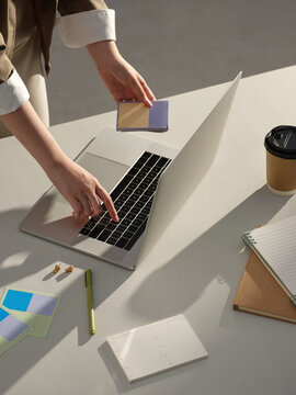 Someone works on a laptop, managing notes at working desk
