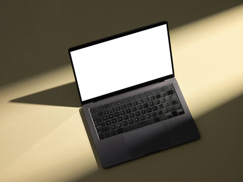 A laptop on a neutral background with light and shadows