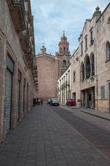 Streets, landscapes, and architecture of Morelia, Michoacan, Mexico, Pink quarry towers of the cathedral in the historic center with a blue sky with clouds. back street