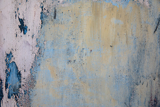Close-up of a weathered, textured surface with layers of blue and pink