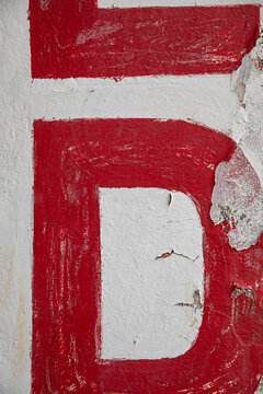 An abstract close-up featuring a red letter 'D' on a textured white wa