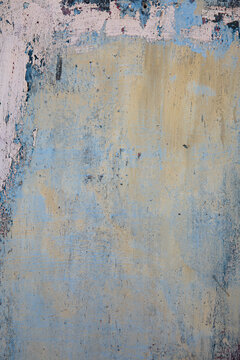 Close-up of a weathered, textured surface with layers of blue and pink