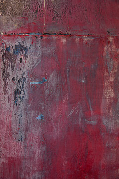 Close-up of a weathered, textured surface with layers of red and dark 