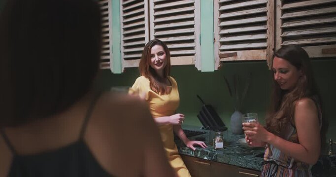 Three women chatting and laughing in studio kitchen