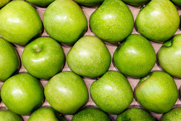 Fresh green apples arranged neatly in a grid pattern, showcasing their vibrant color and smooth texture, ideal for healthy eating and culinary presentations
