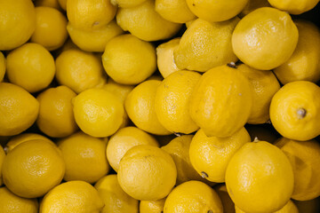 Fresh yellow lemons piled together in a vibrant display, showcasing their textured skin and bright color, representing healthy eating and natural produce