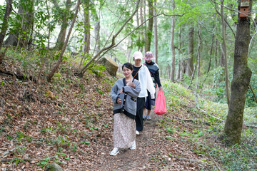 A woman is walking in the woods with two other people. She is wearing a black and white sweater