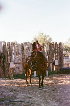 Cowgirl riding horse in corral