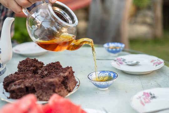 Pouring Tea and Serving Cake at an Outdoor Gathering