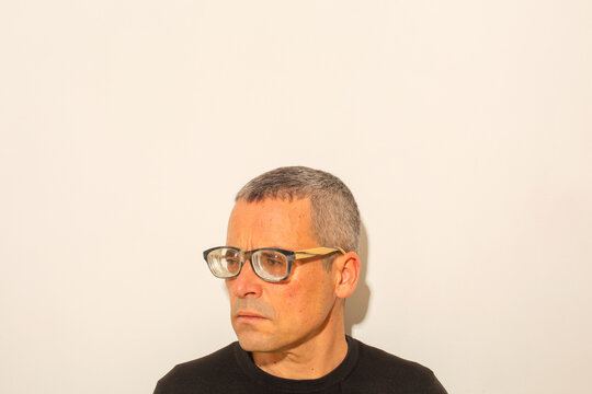 Thoughtful Man in Worn Thick Glasses Against Neutral Background

