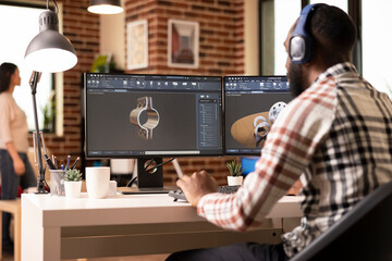 African american man with headphones, analyzing design on monitor using cad software. Innovative remote designer listening to music and working on construction tool simulation from brick wall home.
