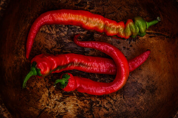 red chili peppers with green tops in rustic vintage wooden bowl