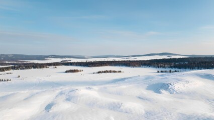 Snowy winter landscape with hills and forest under blue sky, peaceful nature scenery with copy space