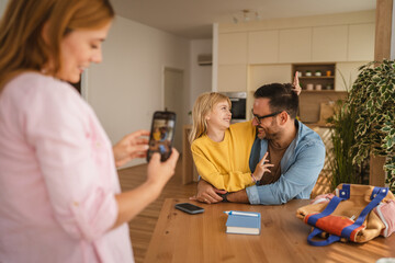 Fototapeta premium Mother taking photo of father and daughter having fun at home