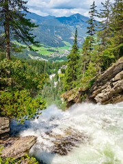 Krimml, Austria - 08-06-2025 : Waterfall flowing down shot from above at the  Krimml Waterfalls, mountains in background.