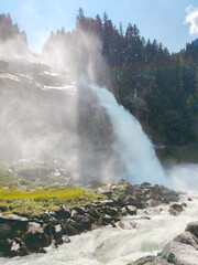 Krimml, Austria - 08-06-2025 : Wide shot of a waterfall flowing down between the forest at the  Krimml Waterfalls.