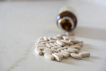 Medical pills spilling from bottle onto white table