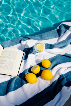 Still life of an open book, a glass of lemonade, and lemons on a towel