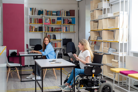 Disabled woman in wheelchair working on tablet in coworking space