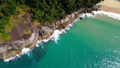 Coastal aerial view of rocks, turquoise water, and jungle