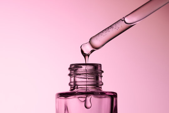 Close-up of a Pipette Releasing Liquid Into a Glass Dropper Bottle.