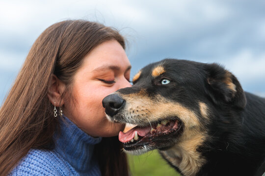 Woman kissing dog with blue eyes