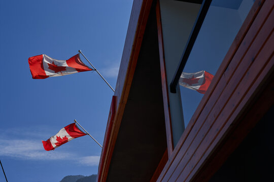 Canadian flags reflected on glass facade