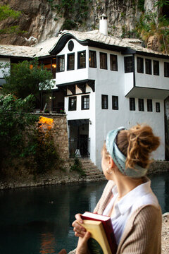 Woman holding books in front of a Buna Dervish House Monastery (Tekija na Buni) in Mostar, Bosnia and Herzegovina