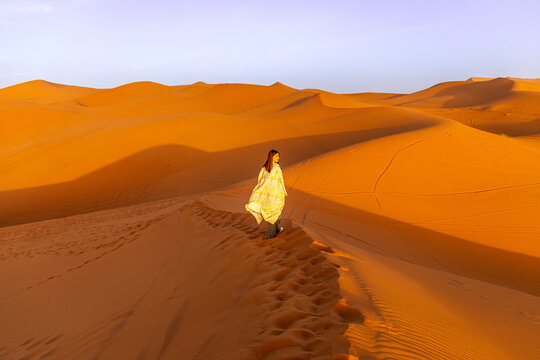 Woman walking on sand dunes in Moroccan desert
