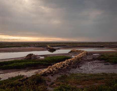 Sunset over marshland with stone structures